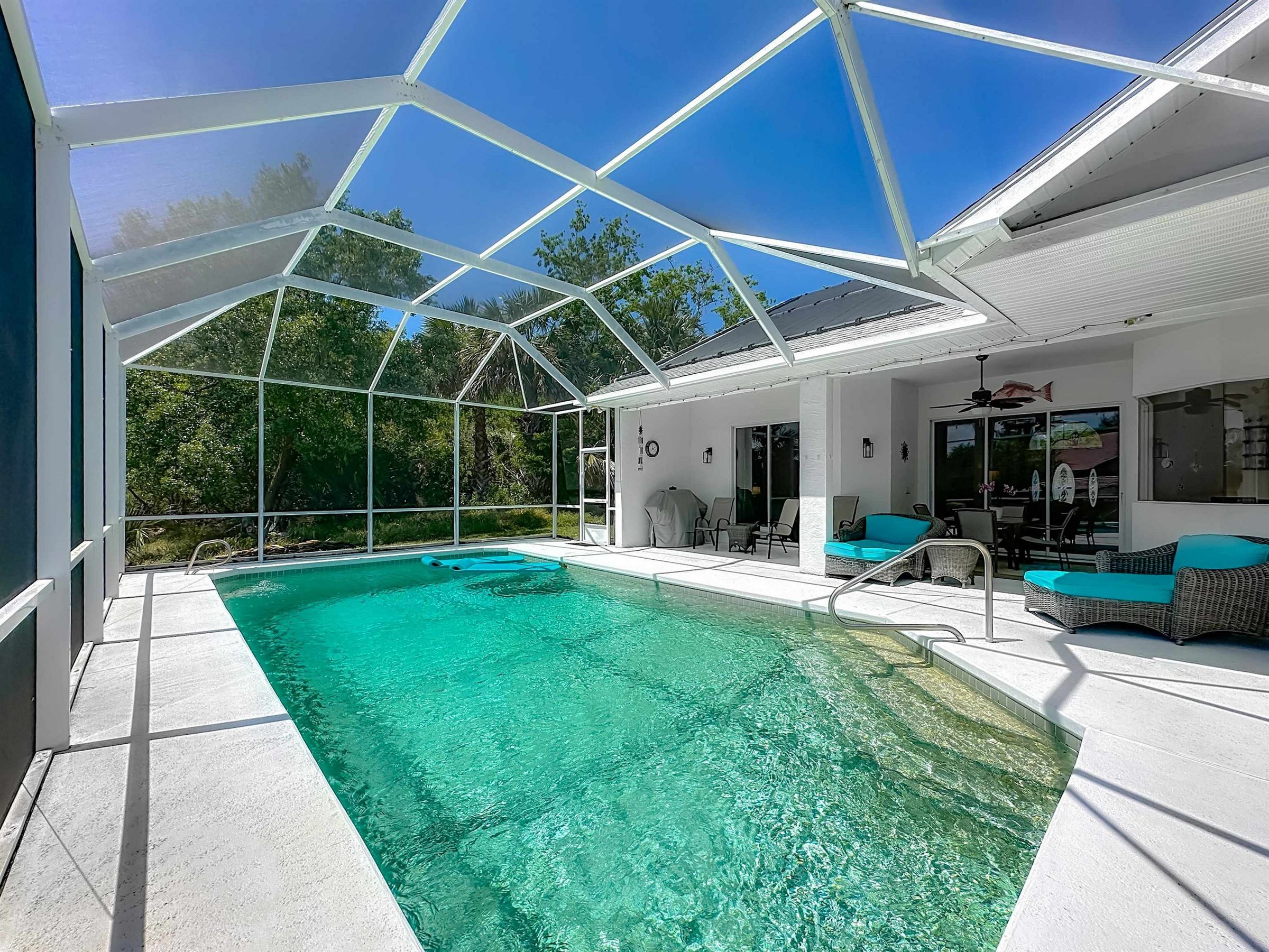 A screened pool and lanai at a Florida home under a bright blue sky